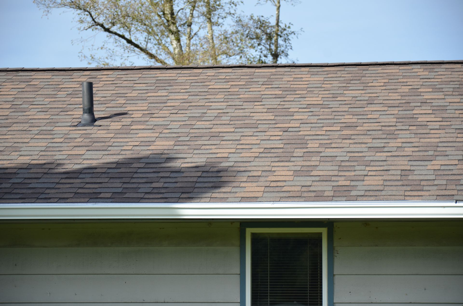 The roof of a house with a window and a chimney on it.