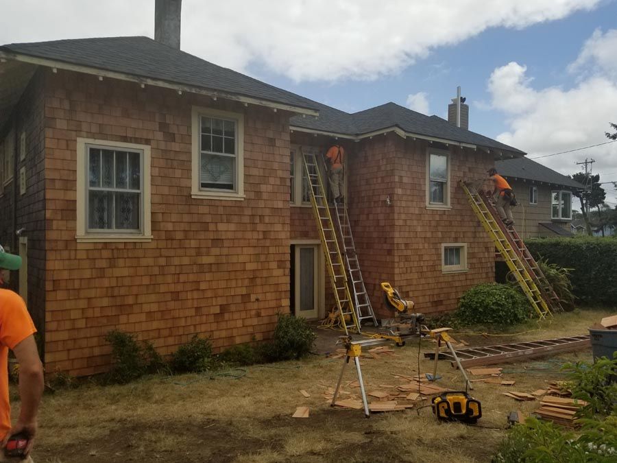 A group of men are working on the side of a large brick house.